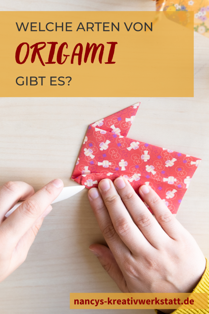 Es wird rotes Origami Papier mit einem weißem Falzknochen gefaltet.