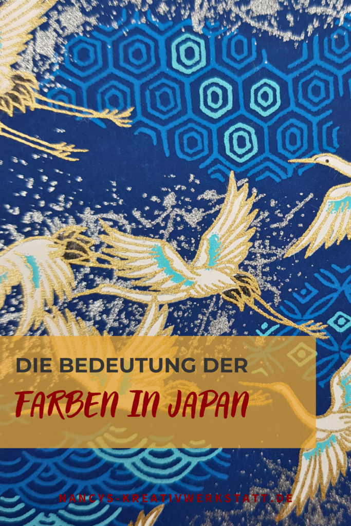 Blaues Origami Papier mit weißen Kranichen die fliegen und der Überschrift "Die Bedeutung der Farben in Japan".